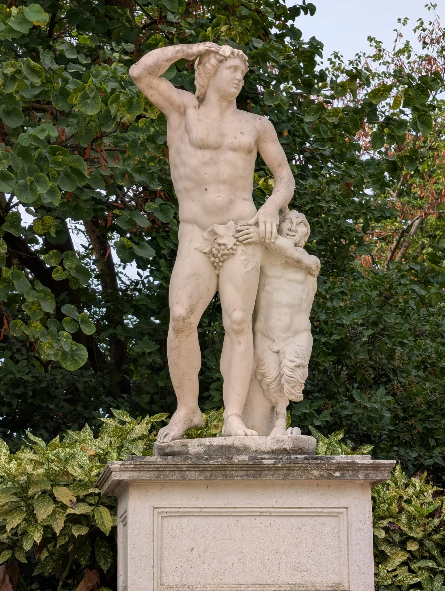 Estatua de mármol de un hombre sosteniendo uvas con una figura más pequeña